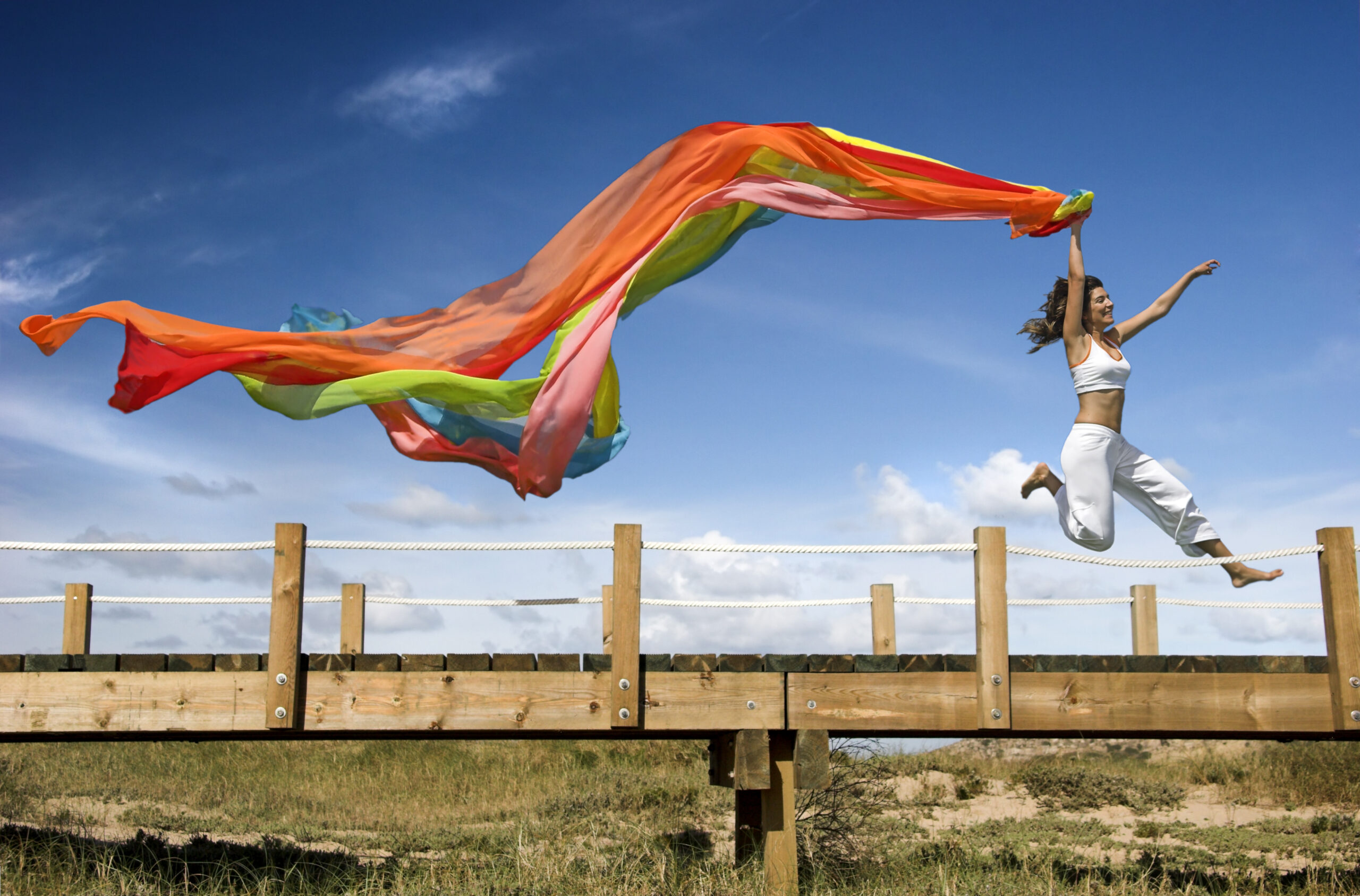 Young beautiful woman jumping with a scarf